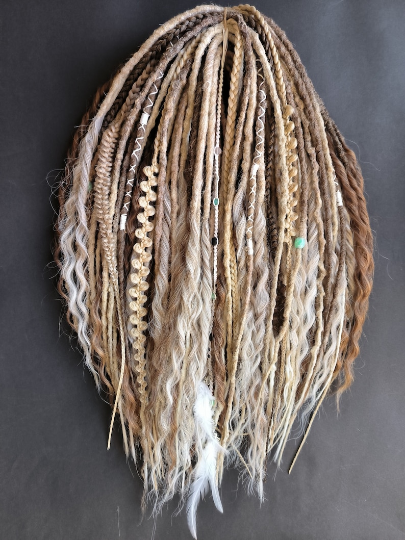 May include: A set of long, brown and blonde synthetic dreadlocks with white and beige accents. The dreadlocks are decorated with beads and feathers.