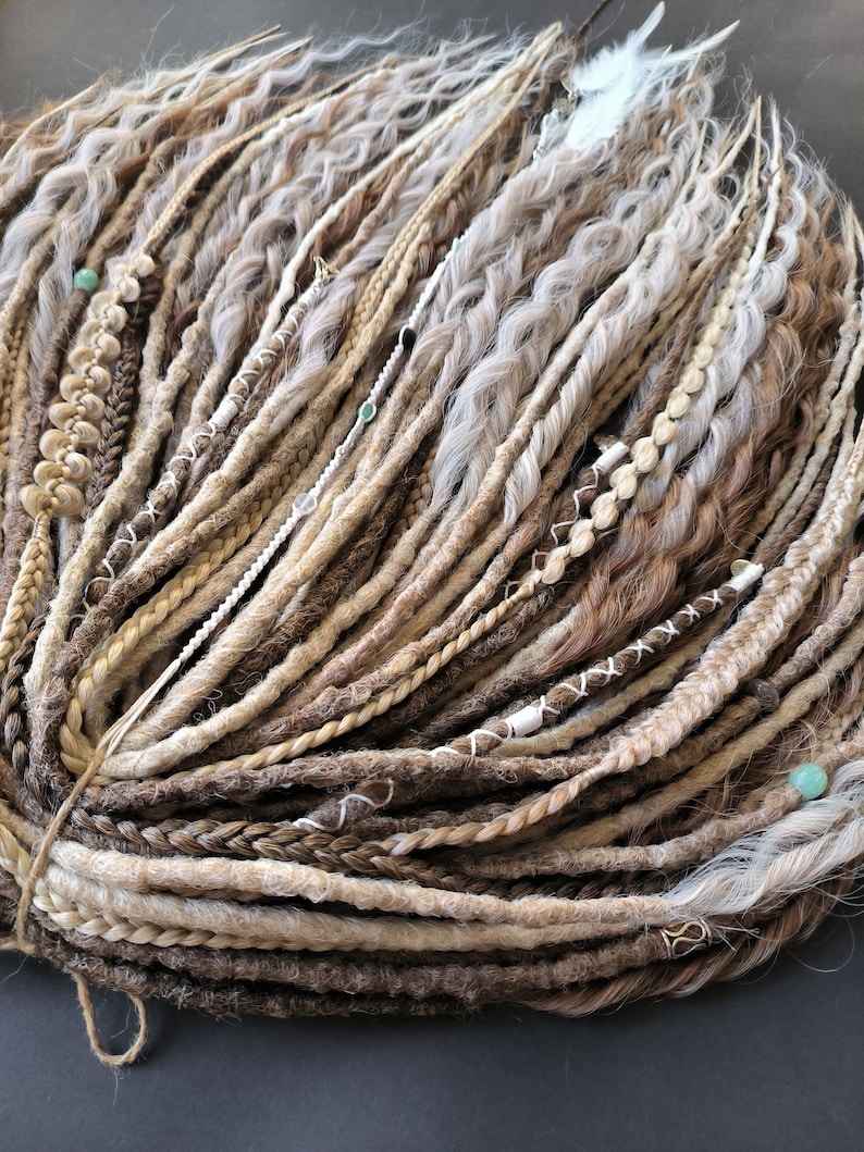 May include: A bundle of synthetic dreadlocks in shades of brown, blonde, and white. The dreadlocks are tied together with a string and have beads and other decorative elements.
