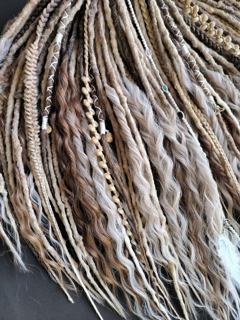 May include: A set of brown, blonde, and white synthetic dreadlocks with beads and charms. The dreadlocks are wavy and have a natural look.