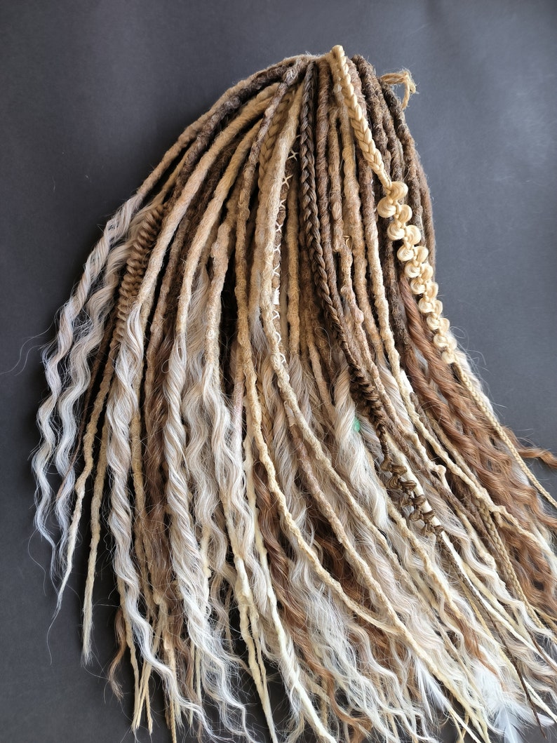 May include: A set of synthetic dreadlocks in shades of brown, beige, and white. The dreadlocks are long and wavy, with some braided sections.