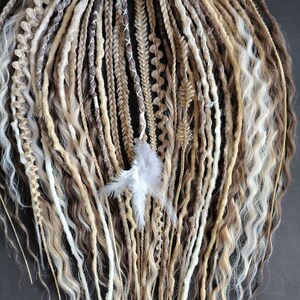 Può includere: Un set di dreadlock sintetiche marroni, bionde e bianche con un accento di piuma bianca. Le dreadlock sono di diverse lunghezze e trame.