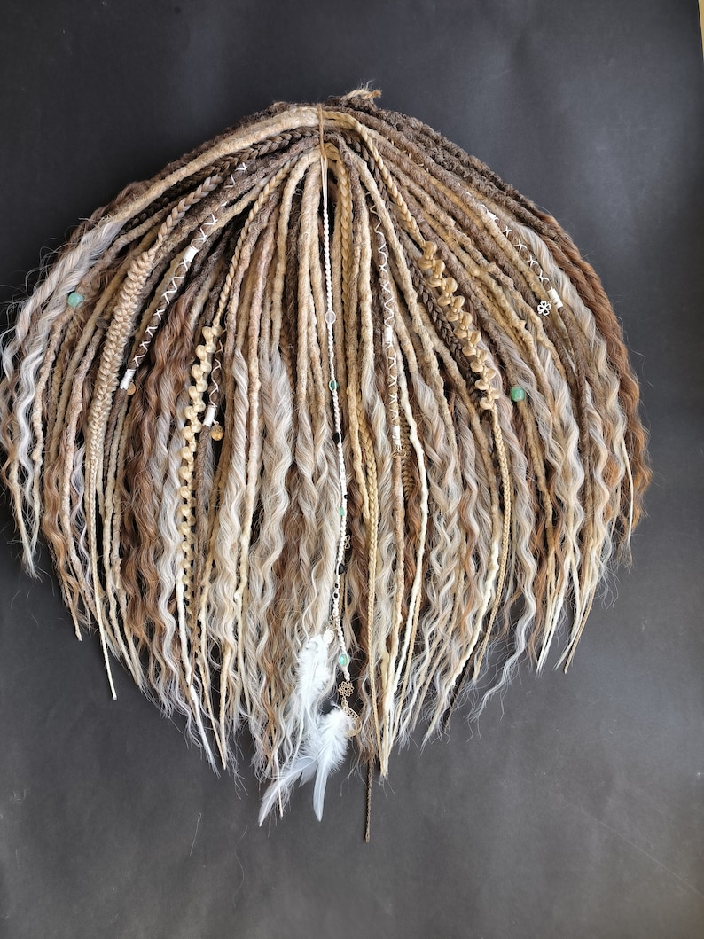 May include: A set of long, wavy synthetic dreadlocks in shades of brown, blonde, and white. The dreadlocks are decorated with beads, feathers, and other embellishments.