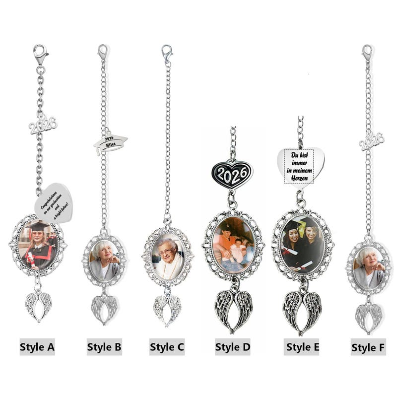 May include: Six silver-toned metal hanging ornaments featuring oval photo frames, chains, and angel wing charms. Styles include graduation caps, the year 2026, and heart-shaped charms with text such as Congratulations on your graduation and Du bist immer in meinem Herzen.