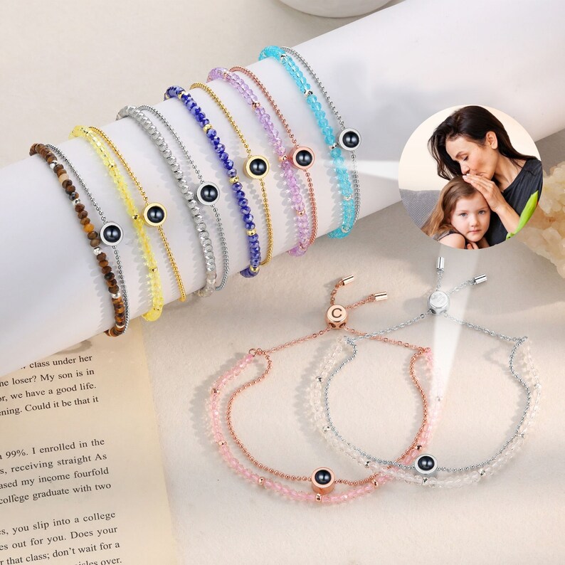May include: A set of colorful beaded bracelets with a hidden photo charm. Each bracelet features a different color of beads and a small, round charm with a hidden photo inside. The charms are silver with a black center. The bracelets are adjustable with a sliding knot.