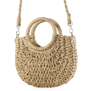 May include: A straw tote bag with a round handle and a long strap. The bag is made of natural straw and has a light brown color.