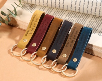 May include: Seven leather keychains with gold rings. Each keychain has the Italian phrase "Guida con prudenza, ho bisogno dite" engraved on it. The keychains are in different colors: yellow, red, brown, dark blue, and gray.