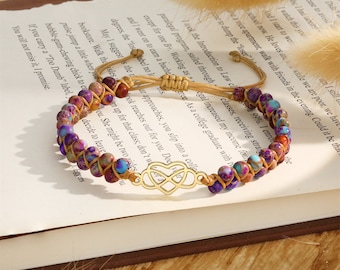 Pode incluir: Duas pulseiras com um fecho de coração infinito dourado. As pulseiras são feitas de cordão marrom e contas de pedra coloridas. As contas são roxas, azuis e marrons.
