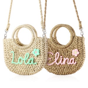 May include: Two straw handbags with personalized names, "Lola" and "Elina", embroidered in green and pink thread. Each bag has a small flower embellishment and a long strap.