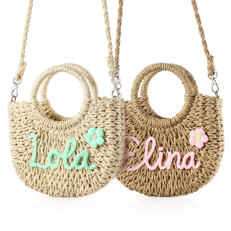 May include: Two straw handbags with personalized names, "Lola" and "Elina", embroidered in green and pink thread. Each bag has a small flower embellishment and a long strap.
