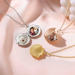 May include: Two silver and one gold shell-shaped photo locket necklaces. The lockets open to reveal a space for a photo. The silver lockets have photos of a girl and a dog, and a dog. The gold locket has a photo of a couple.