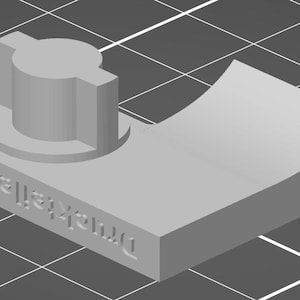 Könnte beinhalten: Ein grauer Kunststoffknopf mit runder Oberseite und quadratischer Basis. Der Knopf ist mit "Dremel 438" beschriftet.