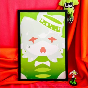 May include: A framed print of a green and white cartoon character with a white hat and bow tie. The character has red eyes and a pink nose. The background is green with white dots.