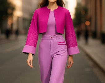 May include: A magenta-colored, cropped jacket with flared sleeves and a matching lavender pantsuit. The jacket has a round neckline and the sleeves have a feathered design. The pants are high-waisted with a straight leg.