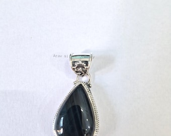 May include: A teardrop-shaped pendant with a dark blue stone, set in a silver-colored metal frame. The pendant has a decorative bail and a textured border. The background is plain white.