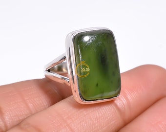 May include: A silver ring with a rectangular green gemstone set in a bezel setting.