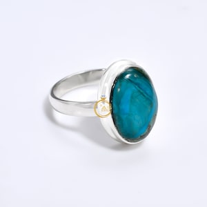May include: A silver ring with a large oval turquoise gemstone. The gemstone has a blue and green color with a marbled pattern.