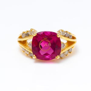 Peut inclure: Une bague en or ornée d'une grosse pierre précieuse rose vif de taille carrée au centre. La bague est ornée de petites pierres précieuses claires le long de la bande et présente un design à tige fendue. La bague porte le texte "AS JEWELRY" sur la pierre précieuse.