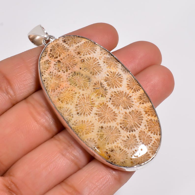 Peut inclure: Un pendentif en argent avec une pierre de corail fossilis&eacute;e de couleur brun clair et beige. La pierre pr&eacute;sente un motif unique de petits cercles.