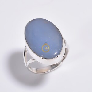 May include: A silver ring with a light blue oval gemstone. The ring has a simple design with a smooth band.