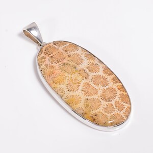 Peut inclure: Un pendentif en argent avec une incrustation ovale de corail fossilis&eacute; brun clair. Le corail pr&eacute;sente un motif d&eacute;taill&eacute; de petites formes de fleurs blanches.