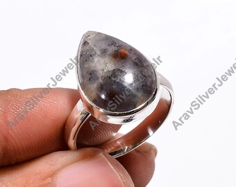 Può includere: Un anello d'argento con una pietra preziosa a forma di lacrima. La pietra preziosa è un mix di grigio, nero e marrone con una finitura scintillante.