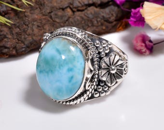 May include: A silver ring featuring a large oval blue and white gemstone set in a floral design.