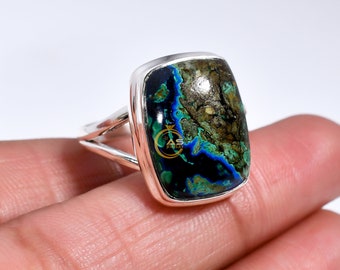 Könnte beinhalten: Ein silberner Ring mit einem großen, rechteckigen, grün-blauen Edelstein. Der Edelstein hat ein einzigartiges, marmoriertes Muster.