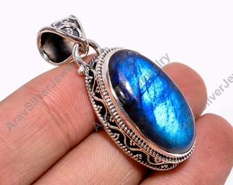 May include: A silver pendant with a blue labradorite gemstone set in an ornate silver frame. The pendant has a bail for attaching to a chain.