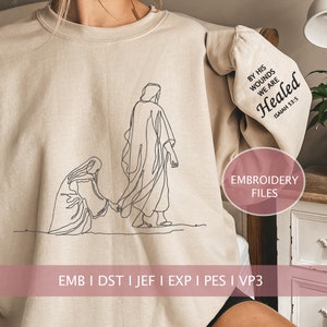May include: Beige sweatshirt with a line drawing of a woman kneeling and a man walking away. The text "By His Wounds We Are Healed Isaiah 53:5" is on the sleeve. The text "Embroidery Files" is on a pink circle. The text "Emb I Dst I Jef I Exp I Pes I Vp3" is at the bottom of the image.