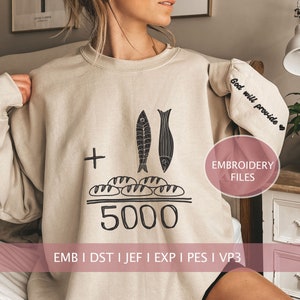 Puede incluir: Sudadera beige con un diseño bordado en negro de dos peces y cinco panes, con el texto "+" y "5000" debajo. El texto "God will provide" está bordado en la manga. El texto "EMBROIDERY FILES" está en un círculo rosa en el lado derecho de la imagen. El texto "EMB I DST I JEF I EXP I PES I VP3" está en la parte inferior de la imagen.