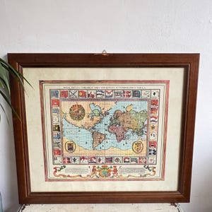 Può includere: Una tazza di ceramica bianca con manico nero e la scritta "But First, Coffee" in grassetto nero. La tazza è appoggiata su una superficie di legno. La tazza è alta circa 10 cm.