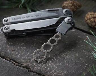 May include: A black Leatherman multi-tool with a silver wrench attachment. The tool is open and the wrench is attached to the side.