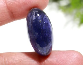 May include: A deep purple, oval-shaped gemstone with a smooth, polished surface. The stone has a slightly cloudy appearance, with flecks of lighter purple throughout.