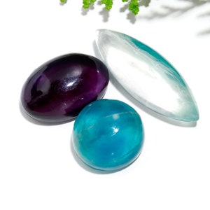 Könnte beinhalten: Drei polierte Edelsteine: ein violettes Oval, eine blaue Kugel und ein weißes, längliches Oval.