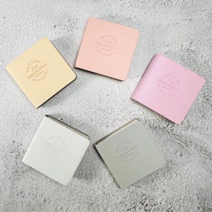 May include: Five square notebooks in pastel colors including yellow, light pink, bright pink, white, and light gray. Each notebook features a debossed circular logo on the front cover with the text Painting Art inspiration NOTEBOOK.