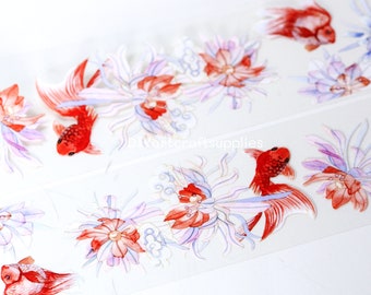 Könnte beinhalten: Eine Rolle Washi-Tape mit einem sich wiederholenden Muster aus roten Goldfischen, die zwischen weißen und violetten Blumen schwimmen. Das Band befindet sich auf einem weißen Hintergrund.