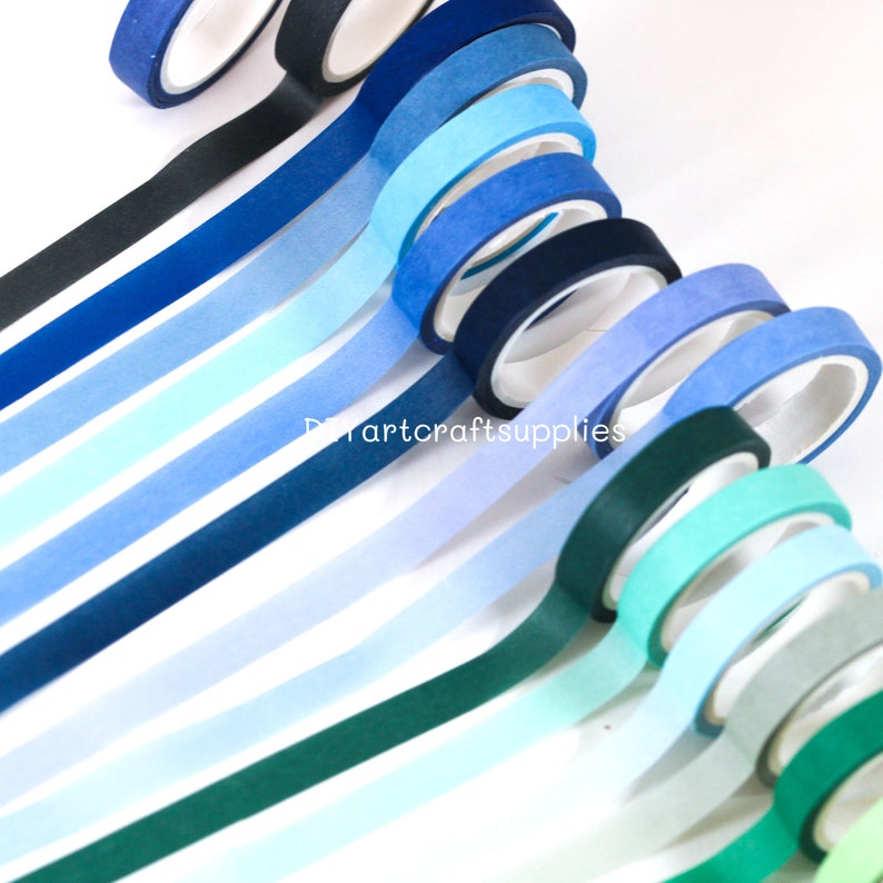 May include: A collection of 12 washi tapes in shades of blue, green, and white. The tapes are arranged in a gradient pattern, with the darkest blue at the top and the lightest white at the bottom.