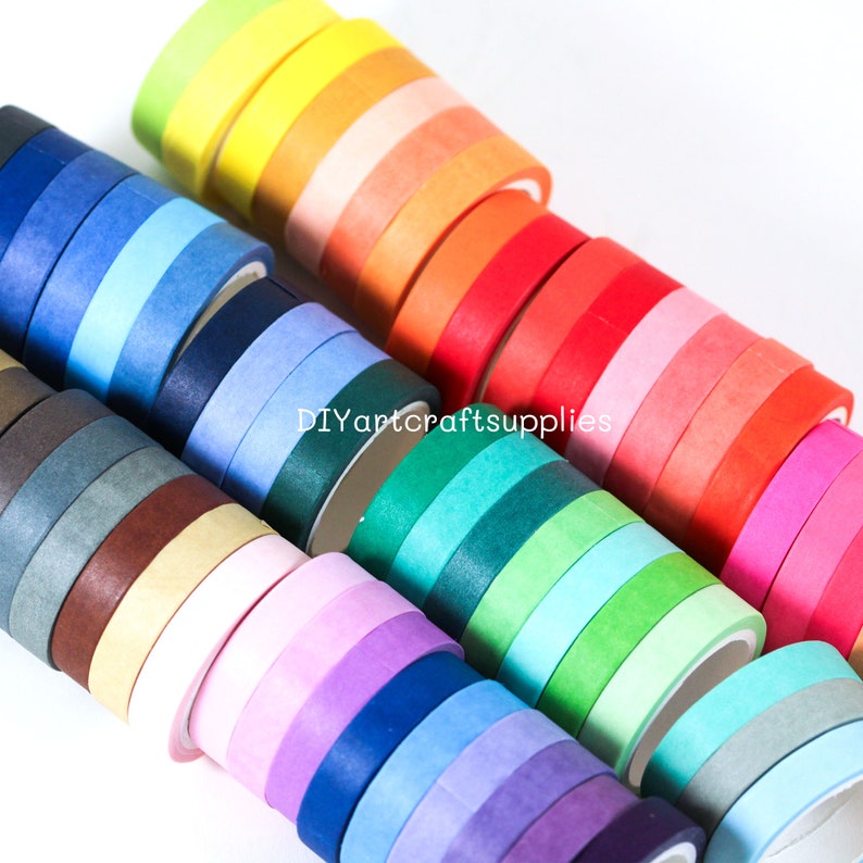 May include: A collection of colorful washi tapes in various shades of blue, green, red, orange, yellow, brown, and pink. The tapes are rolled up and stacked on top of each other. The text "DIYartcraftsupplies" is visible on the image.