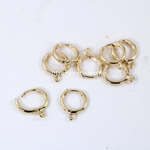 May include: Gold-toned earring hoops with a jump ring for attaching charms or pendants. The hoops are approximately 1 inch in diameter.