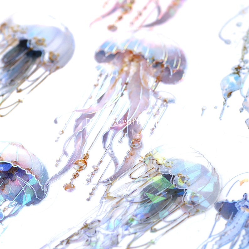 May include: A sheet of iridescent holographic stickers featuring jellyfish in various poses. The stickers are transparent and have a shimmering, rainbow-like effect.