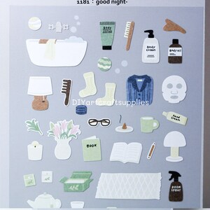 May include: A collection of paper cut-out illustrations with a self-care theme. Includes a bathtub, body scrub, socks, a sweater, a face mask, a book, and other items. The text "good night" is at the top.