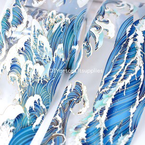 May include: A sheet of clear adhesive vinyl with a repeating pattern of blue and gold waves. The waves are stylized and resemble a traditional Japanese art style.