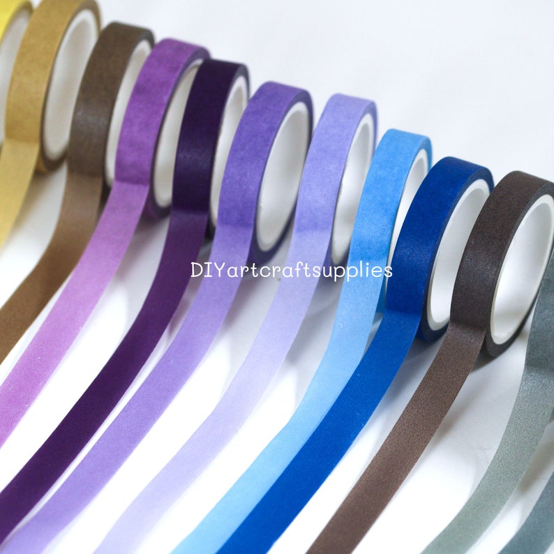 May include: A set of ten washi tapes in a gradient of colors, starting with gold and transitioning to gray. The tapes are arranged in a row, with the gold tape at the top and the gray tape at the bottom. The tapes are all the same width and have a matte finish.