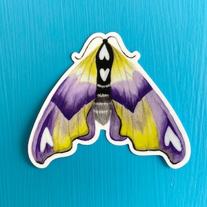 May include: A purple and yellow moth sticker with white heart-shaped markings on its wings.