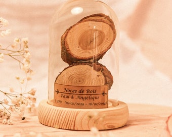 May include: Two wooden rings stacked inside a glass dome on a wooden base. The label reads "Noces de Bois Paul & Angelique 5 ans (16/02/2019 - 16/02/2024)"