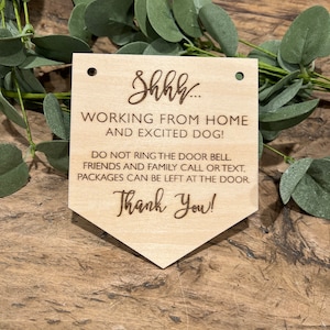 May include: A wooden sign with the text "Shhh... Working from home and excited dog! Do not ring the door bell. Friends and family call or text. Packages can be left at the door. Thank you!"