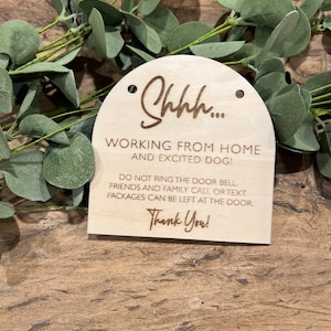 May include: A wooden sign with the text "Shh... Working from home and excited dog! Do not ring the door bell. Friends and family call or text. Packages can be left at the door. Thank you!"