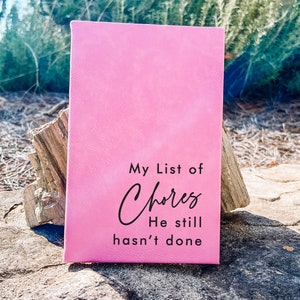 May include: A pink notebook with the text "My List of Chores He still hasn't done" written on the front.