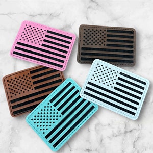 May include: Five American flag patches in different colors. The patches are made of leather and have a stitched border. The colors are pink, brown, white, blue, and turquoise.