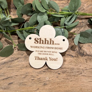 May include: A wooden flower-shaped sign with the text "Shhh... Working from home. Please do not ring the door bell. Thank you!"